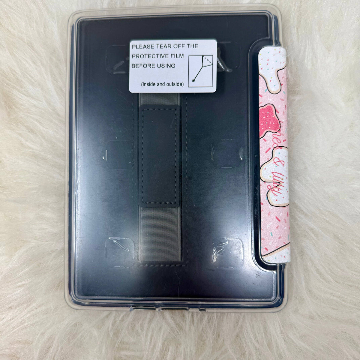 Black E-Reader case with a pink and white patterned strip on a light brown surface