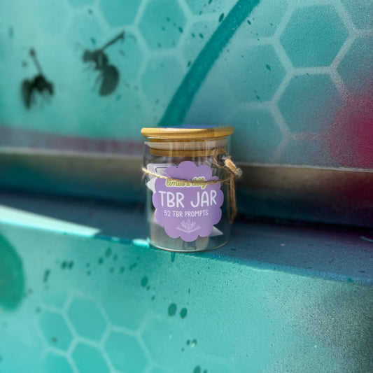 Small glass jar labeled 'TBR Jar' on a textured green surface