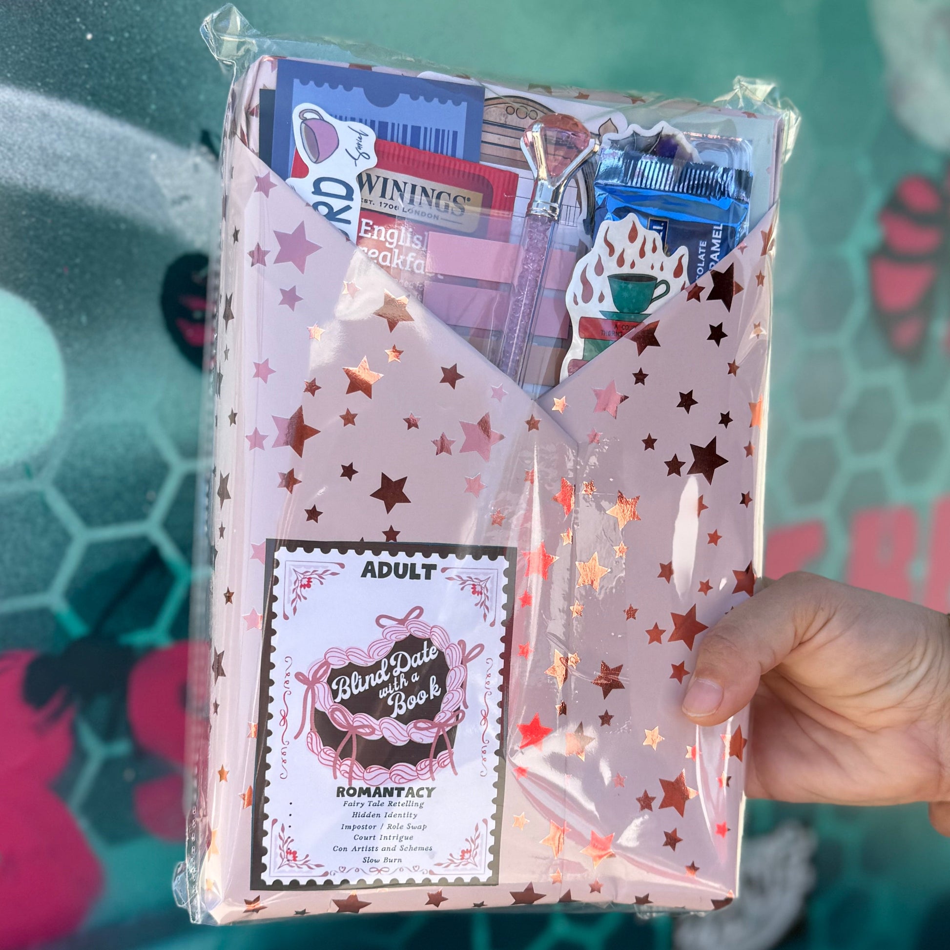 Hand holding a package with star designs against a colorful, graffiti-style background