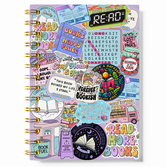 A spiral-bound notebook with a lavender cover covered in colorful book-themed stickers and illustrations, including a large 'READ' clock graphic and phrases like 'Books happy flags' and 'Read more books.'.