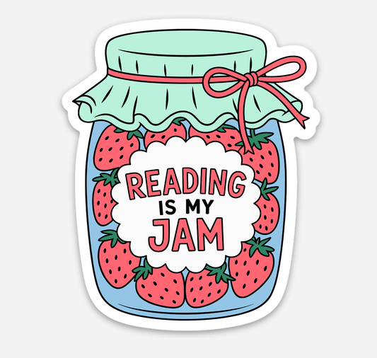 A die-cut sticker featuring a cartoon illustration of a glass jar filled with red strawberries and topped with a mint green cloth and red ribbon. A white cloud-shaped label in the center reads “READING IS MY JAM” in red and black text, shown on a light gray background.