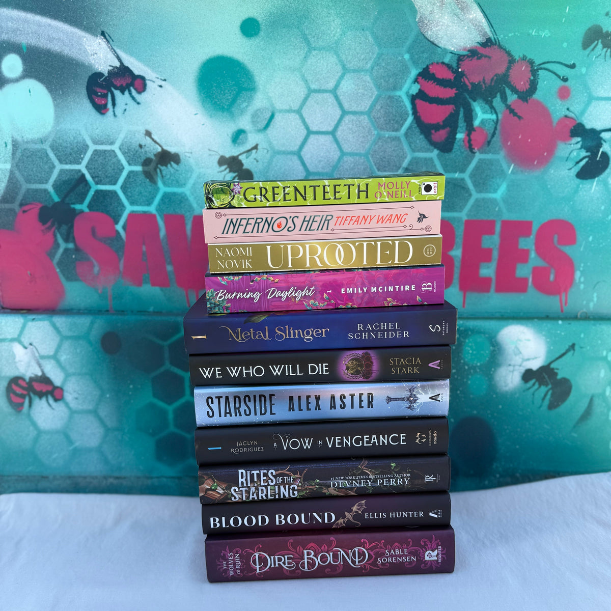 Stack of books with colorful covers against a colorful background with bee designs.